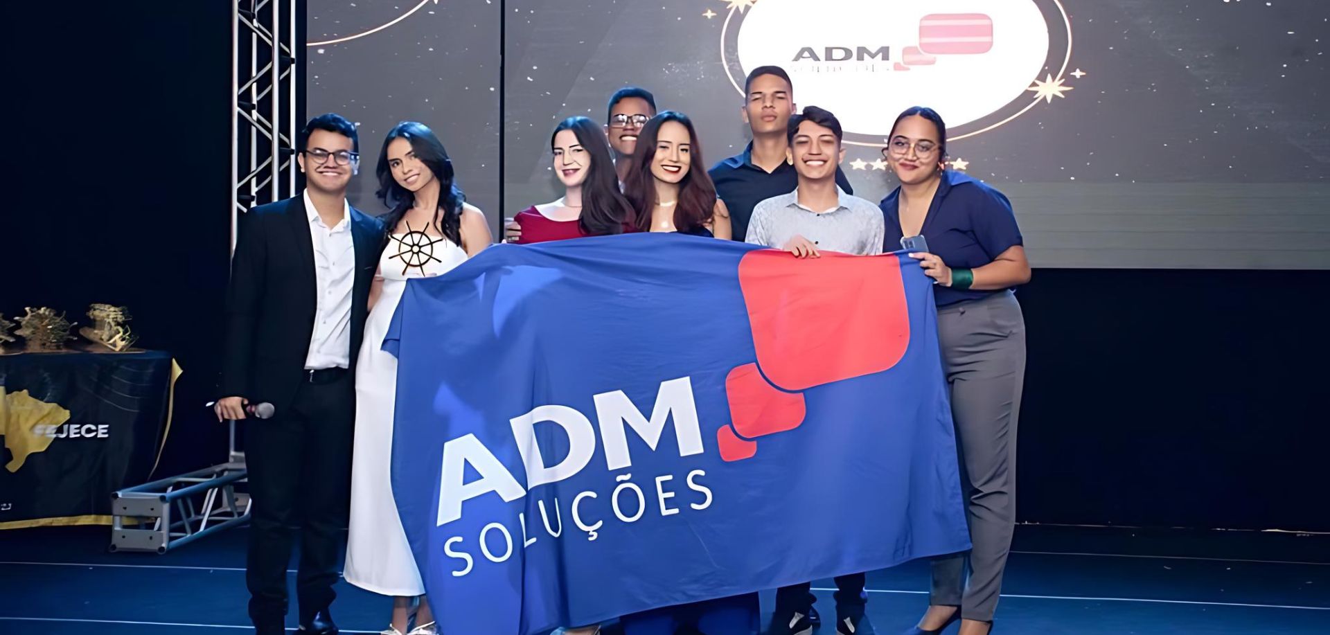 Consultores financeiros da ADM Soluções sendo premiados e segurando a bandeira da empresa